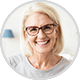 Older woman with grey hair and glasses smiling