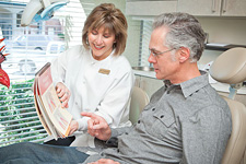 Dental technician showing patient dental diagrams in a book