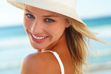 Beautiful woman smiling at the beach with white hat