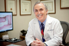 Dr. Briscoe sitting at desk smiling in white coat