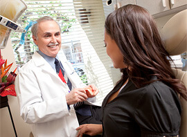 Dr. Briscoe talking with patient while holding teeth model