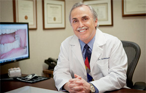 Dr. Charles Briscoe smiling at desk in white coat