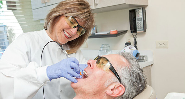 Dental hygienist using pain-free laser on patient