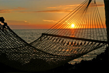 Hammock on the beach with the ocean and sunset in the background